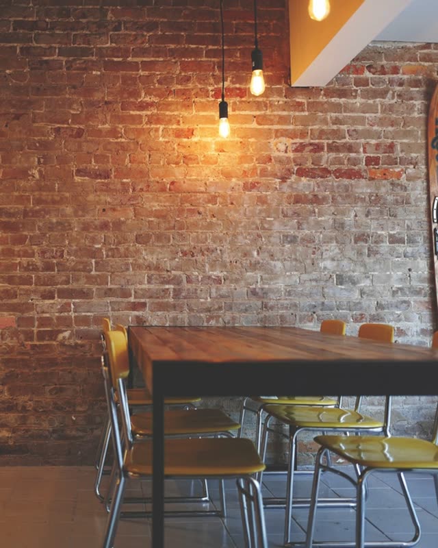 Gemütliches Café mit Backsteinwand, Holztisch und warmem Licht
